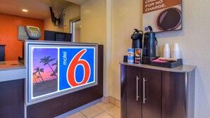 A motel lobby with a reception desk, a coffee station, and a sign indicating the motel number. - Motel 6 Riverside West - Jurupa Valley (Jurupa Valley)