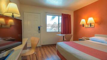 Een hotelkamer met een bed, bureau, stoel en een televisie.