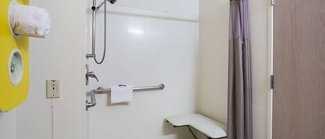 Een badkamer met een douche, toilet en een bankje.