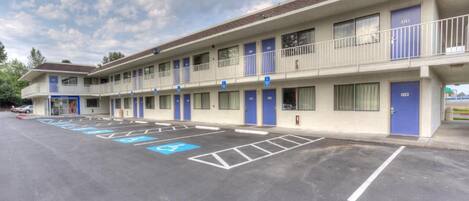 A motel with a parking lot, marked handicapped parking spaces, and a two-story building with balconies.