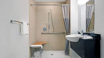 Une salle de bain moderne équipée d’une douche, d’un lavabo, d’un banc et d’un porte-serviettes.