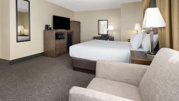 Une chambre d’hôtel comprenant un lit, une télévision, un bureau avec une lampe, une commode et une chaise.