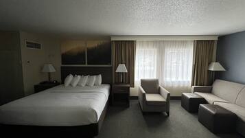 A hotel room with a large bed, two armchairs, a sofa, and two lamps.