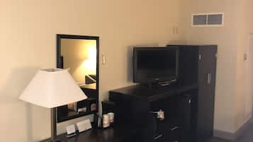 Habitación de hotel con escritorio, silla, televisor y armario.