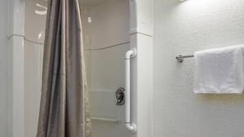 Un espace douche doté d’une porte en verre incurvée, d’un porte-serviettes avec une serviette, et d’un luminaire fixé au mur.