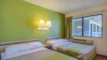 A hotel room with two beds, a nightstand with a phone, and a window with a view of a building.