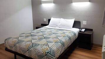 A neatly made bed with a patterned bedspread, two bedside tables with lamps, and a wall-mounted light fixture.