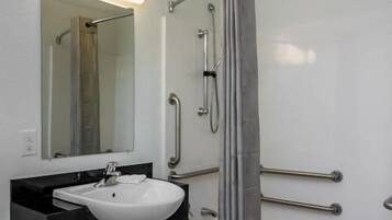 A bathroom with a white sink, mirror, and shower area.