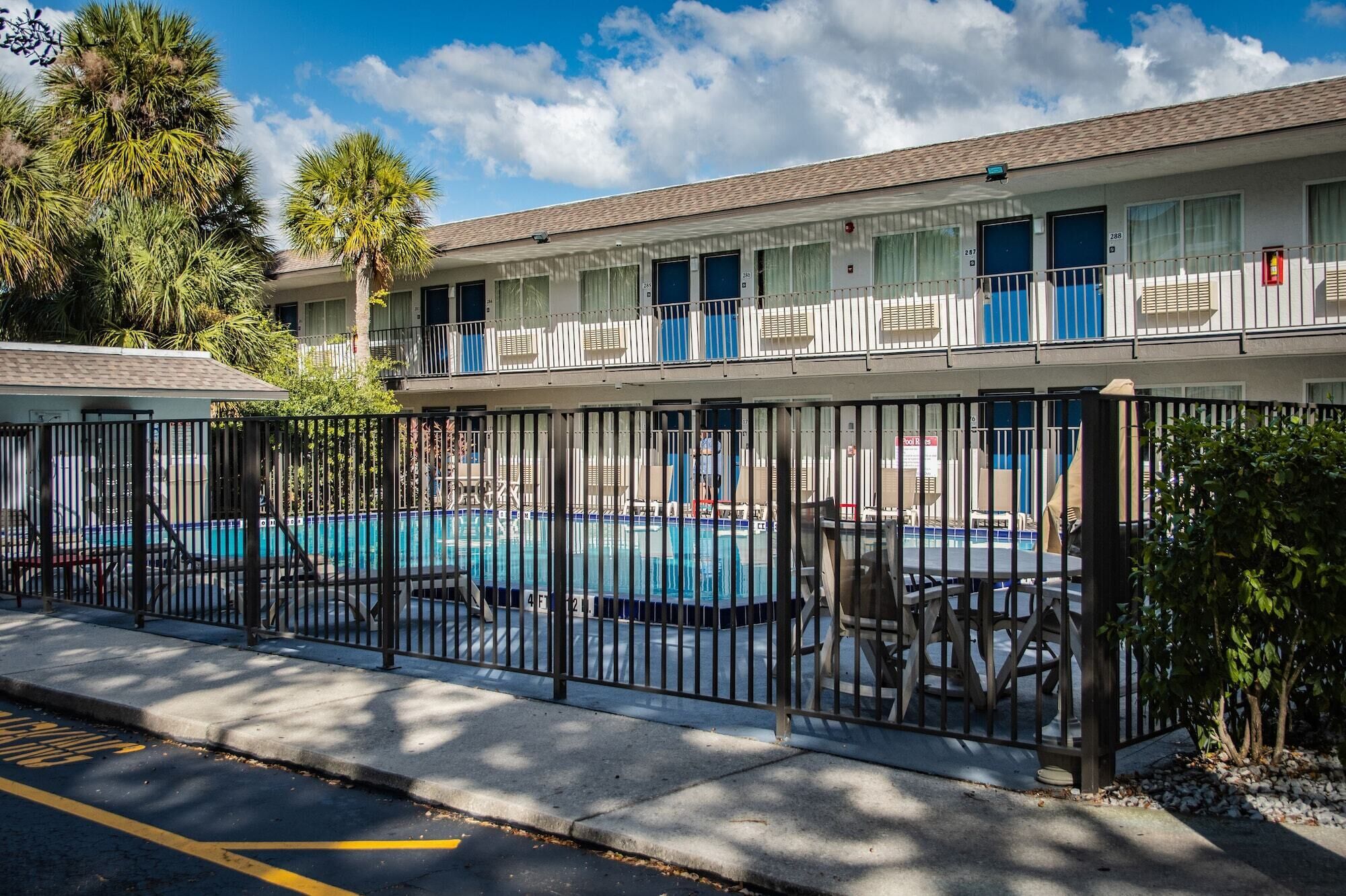 Un motel con piscina, zona vallada y una hilera de habitaciones con balcones.
