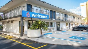A motel with a 'Welcome' sign, a parking lot with handicapped spaces, and a black car parked in front. - Motel 6 Kissimmee, FL - Orlando (Kissimmee)