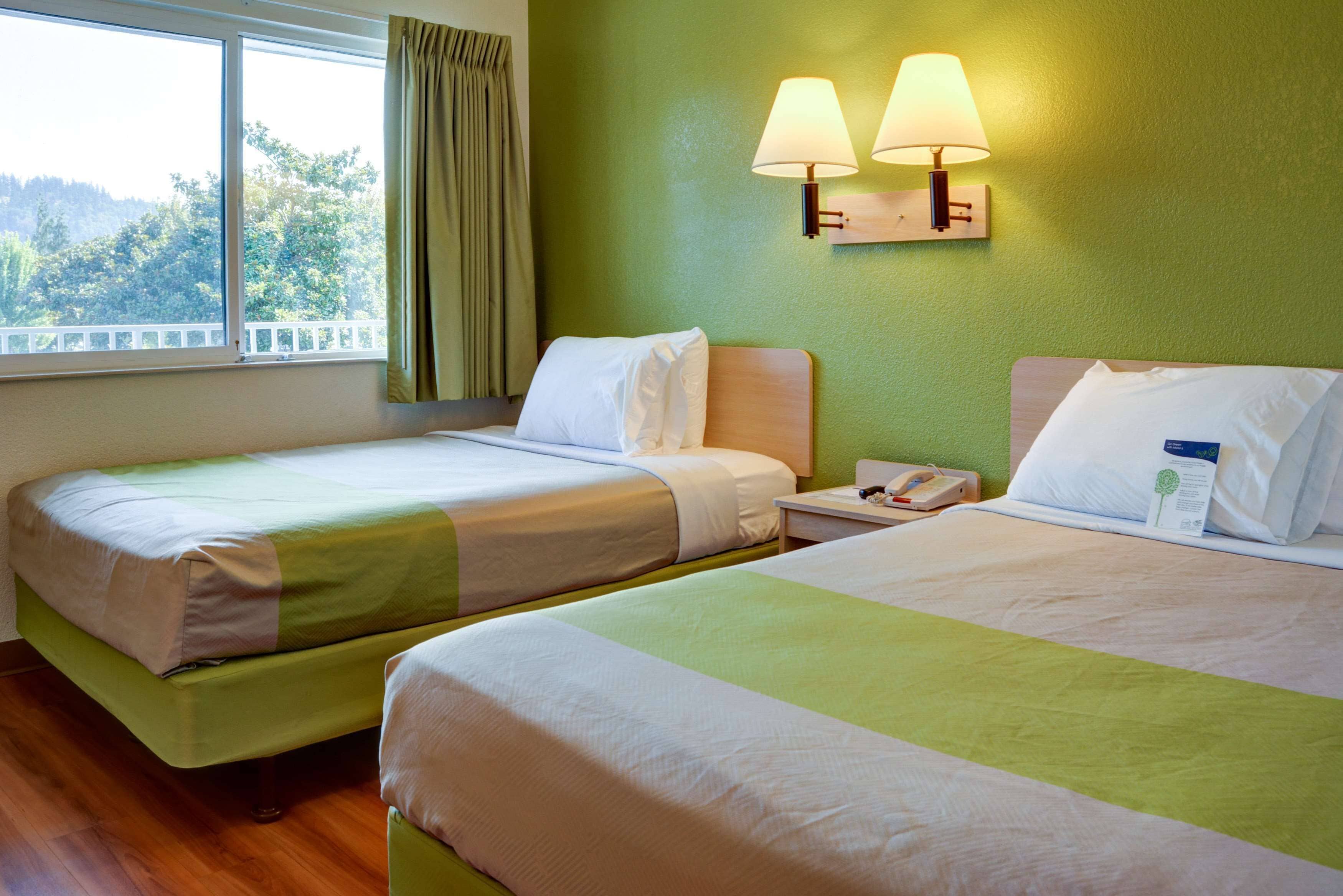 Une chambre d’hôtel avec deux lits, une fenêtre donnant sur un beau paysage et une lampe fixée au mur.