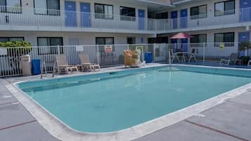 A pool area with lounge chairs and a building with multiple balconies.