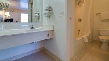 Une salle de bain avec un lavabo blanc, un miroir et un porte-serviettes. On y trouve également une douche avec un rideau et des toilettes.