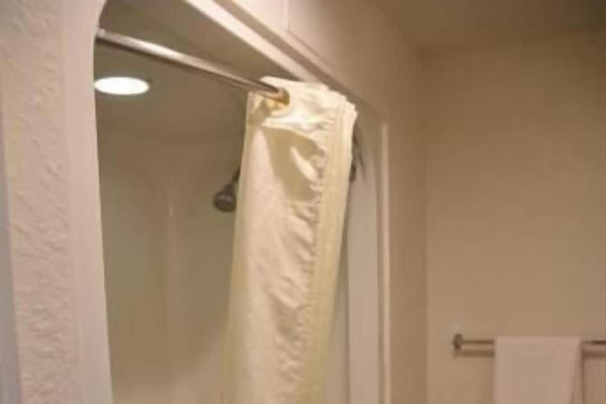 Baño con ducha, inodoro y un estante pequeño con una botella.