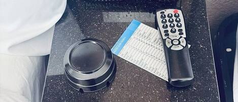 A small bedside table with a phone, a remote control, and a menu card.