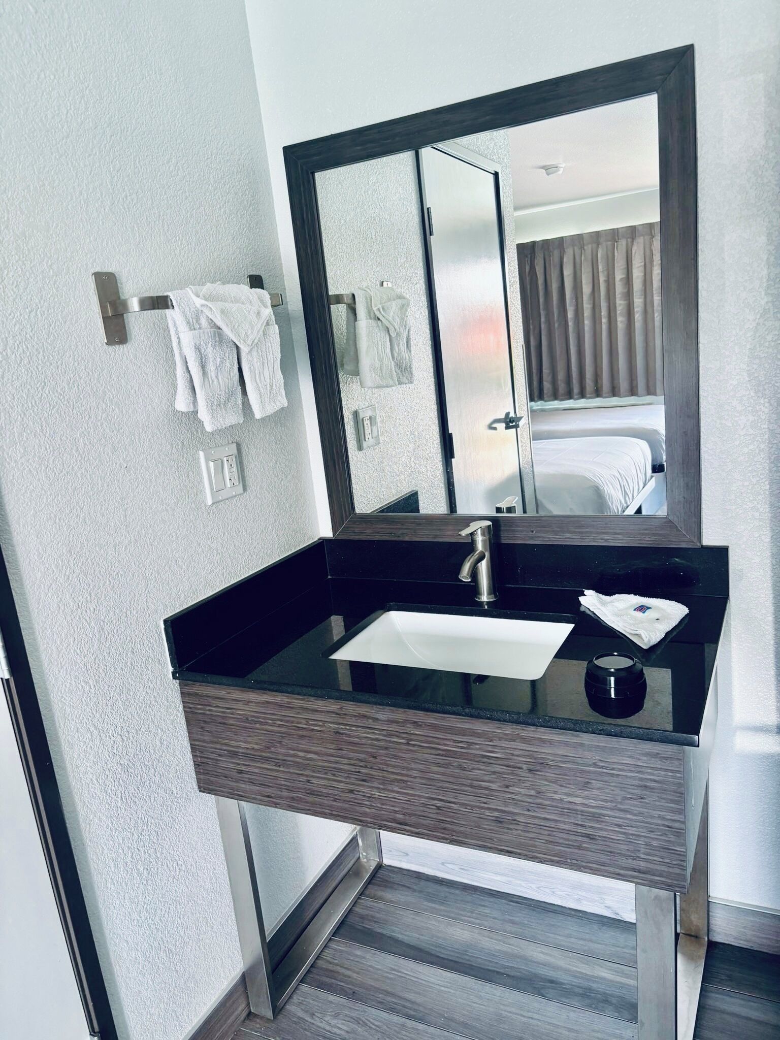 Un baño moderno con un lavabo negro, un espejo y un perchero para toallas.