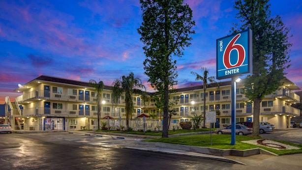 A motel with a '6 Enter' sign, multiple balconies, and a parking lot.