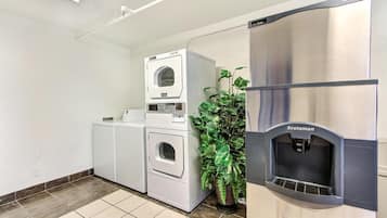 A laundry facility with a front-loading washer, a stacked dryer, and a water dispenser.