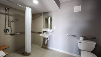 A bathroom with a shower, a sink, a toilet, and a mirror.