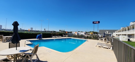 Una piscina al aire libre, sombrillas, sillones reclinables de piscina