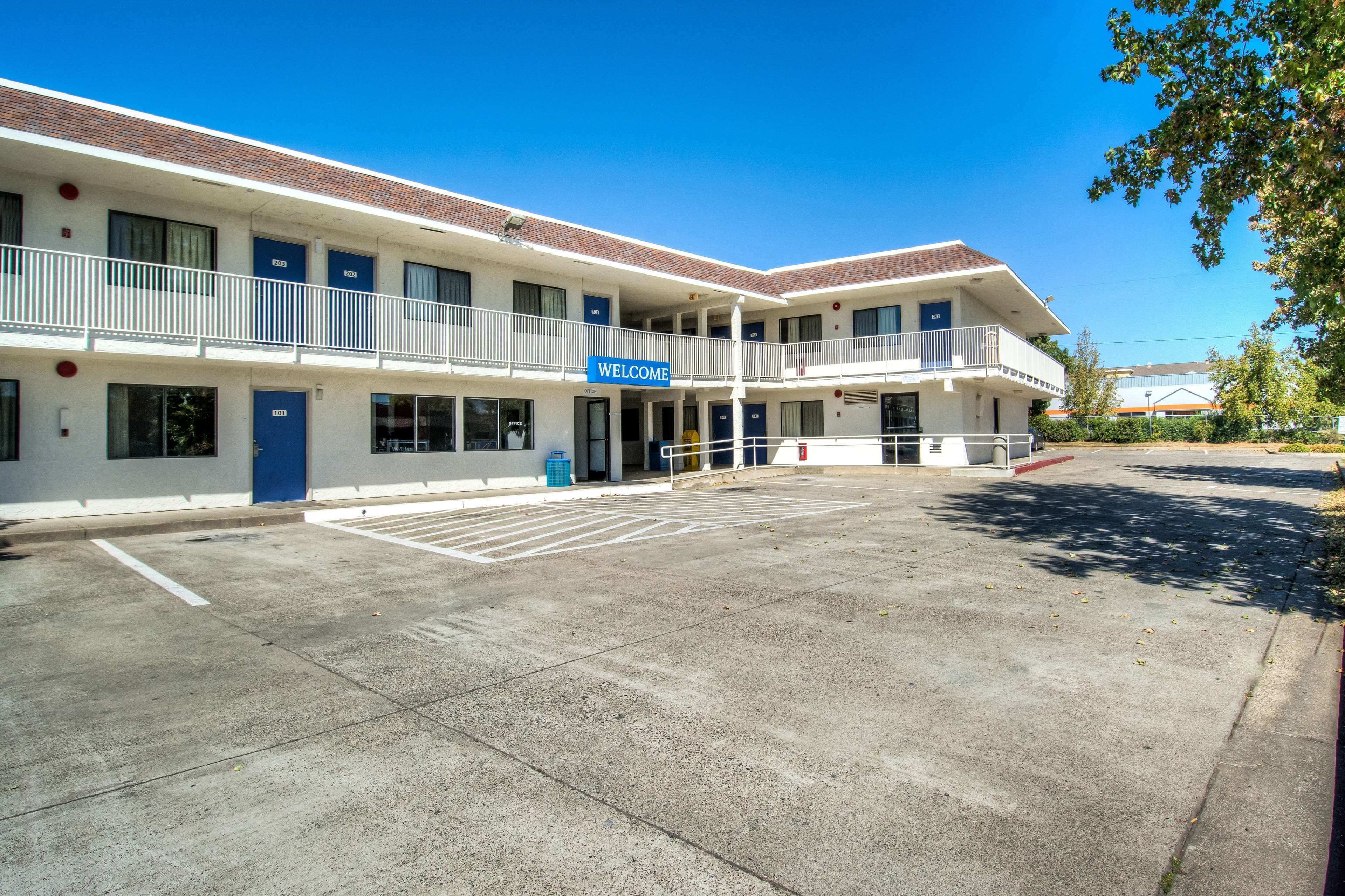 A motel with a 'WELCOME' sign, a parking lot, and a covered outdoor area.