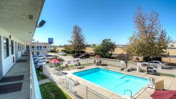A hotel with a swimming pool, outdoor seating, and a clear view of the surrounding landscape.