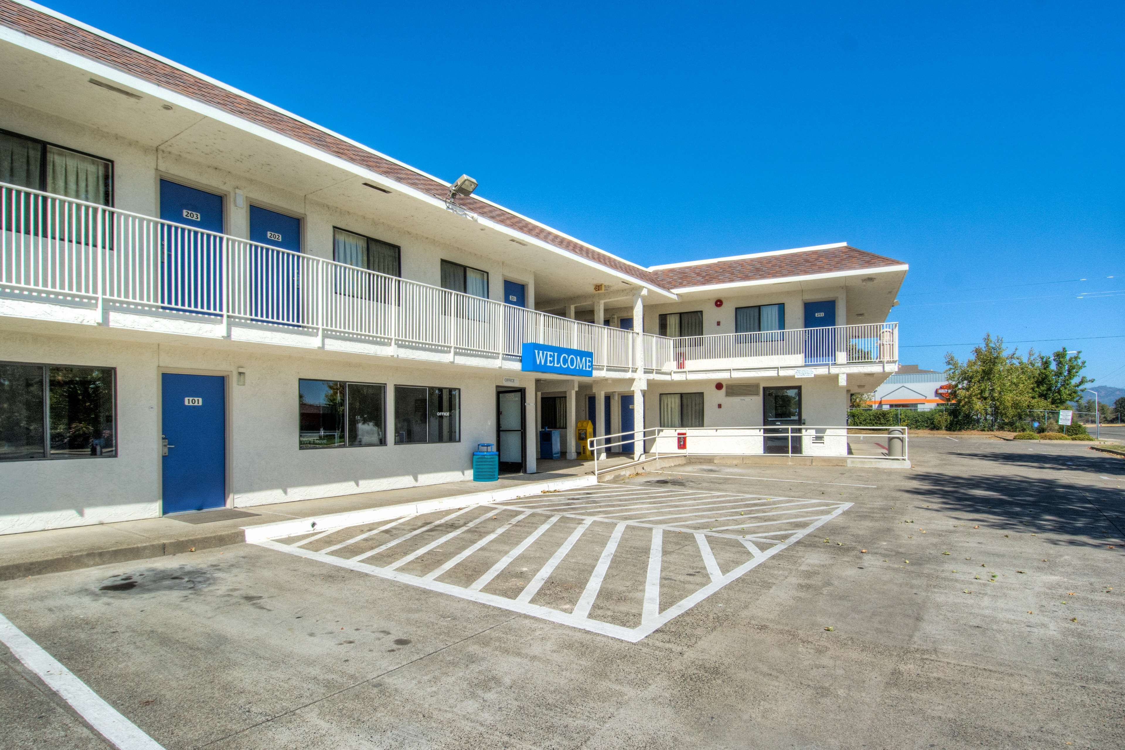 A motel with a 'WELCOME' sign, a parking lot, and a building with multiple balconies.