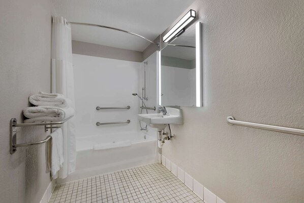 Une salle de bain avec une baignoire, un lavabo, un miroir et un porte-serviettes.
