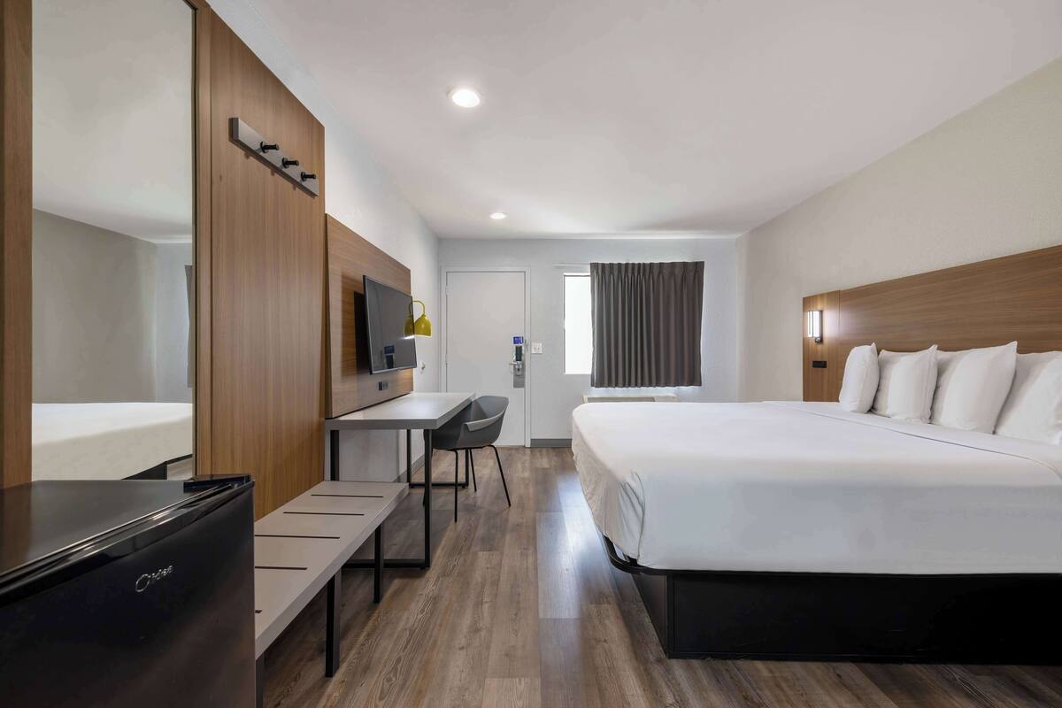 Une chambre d’hôtel comprenant un lit, un bureau, une chaise, une télévision et une armoire.