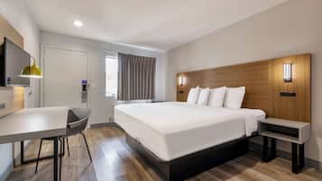 Una habitación de hotel moderna con una cama grande, un escritorio, una silla y un televisor.