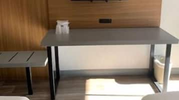 A modern room with a wooden wall, a flat-screen TV mounted above a gray table, and two white beds.