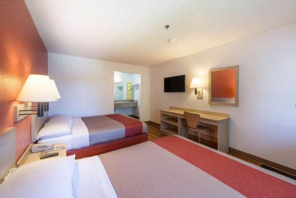 A hotel room with two beds, a desk, a chair, a TV, and a mirror. - Motel 6 Sparks, NV - Airport - Sparks (Sparks)