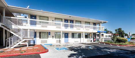 A motel with a two-story structure, a covered parking area, and a wheelchair-accessible entrance.