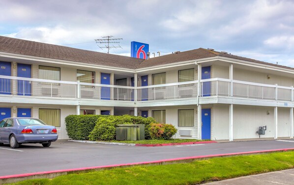 A motel with a two-story structure, numbered rooms, and a visible car parked in front. - Motel 6 Medford, OR - North (Medford)