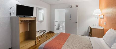 Habitación de hotel con cama, televisión, escritorio y baño.