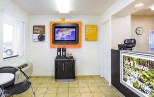 Una zona de recepción con una pantalla digital que muestra información meteorológica, un reloj y un cartel que promociona ahorros para viajes.