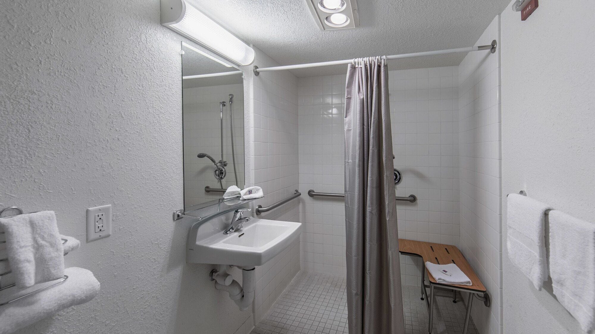 Une petite salle de bain blanche, équipée d’une douche, d’un lavabo et de toilettes.
