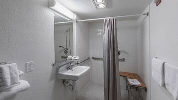 Un baño pequeño y blanco con ducha, lavamanos e inodoro.