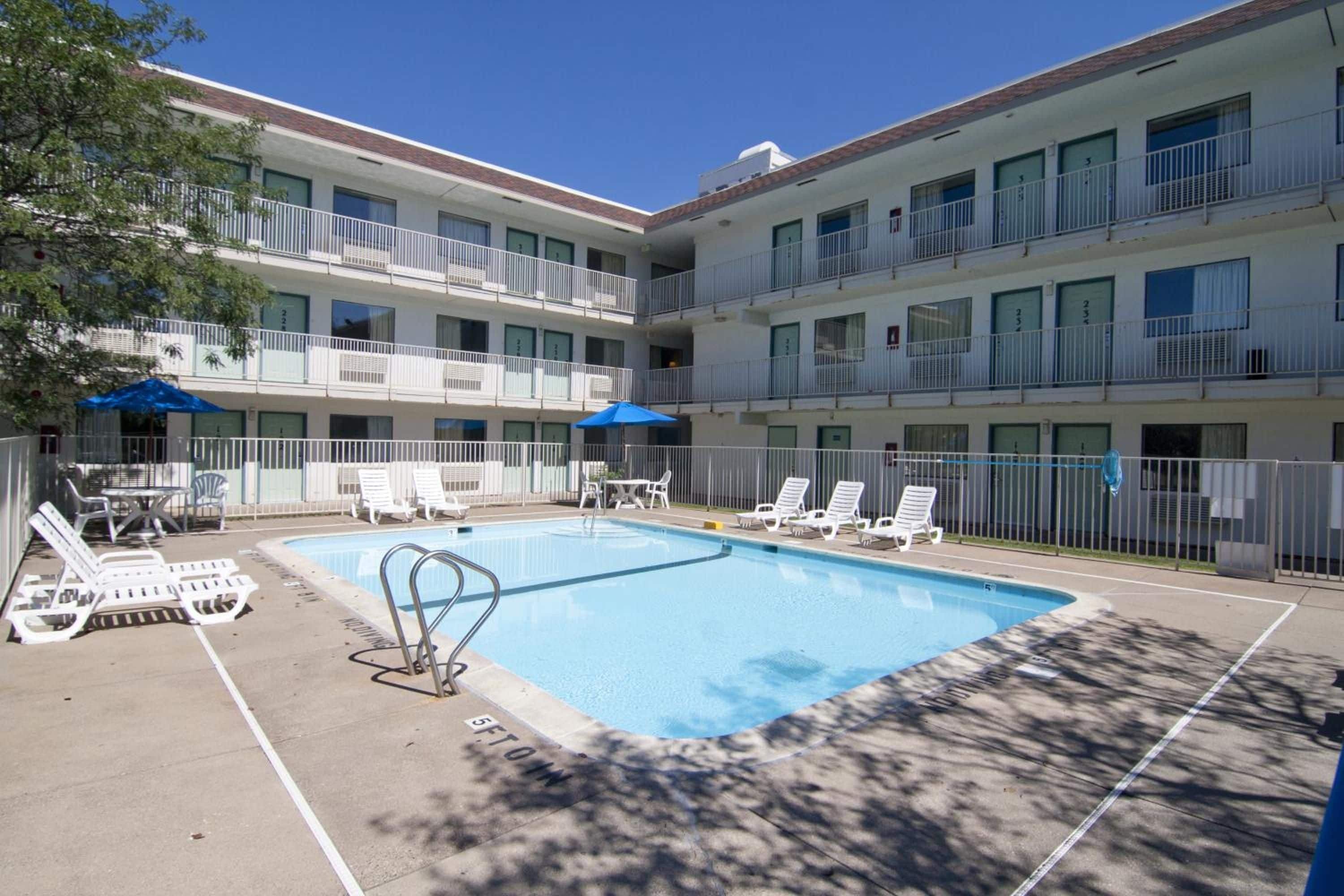 A hotel with a swimming pool, multiple balconies, and outdoor seating.