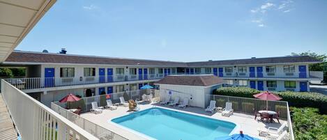 A hotel with a swimming pool, multiple balconies, and outdoor seating areas.