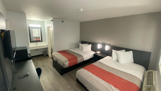 A hotel room with two beds, a desk, a mirror, and a television. - Motel 6 Windsor Locks, CT - Hartford (Windsor Locks)