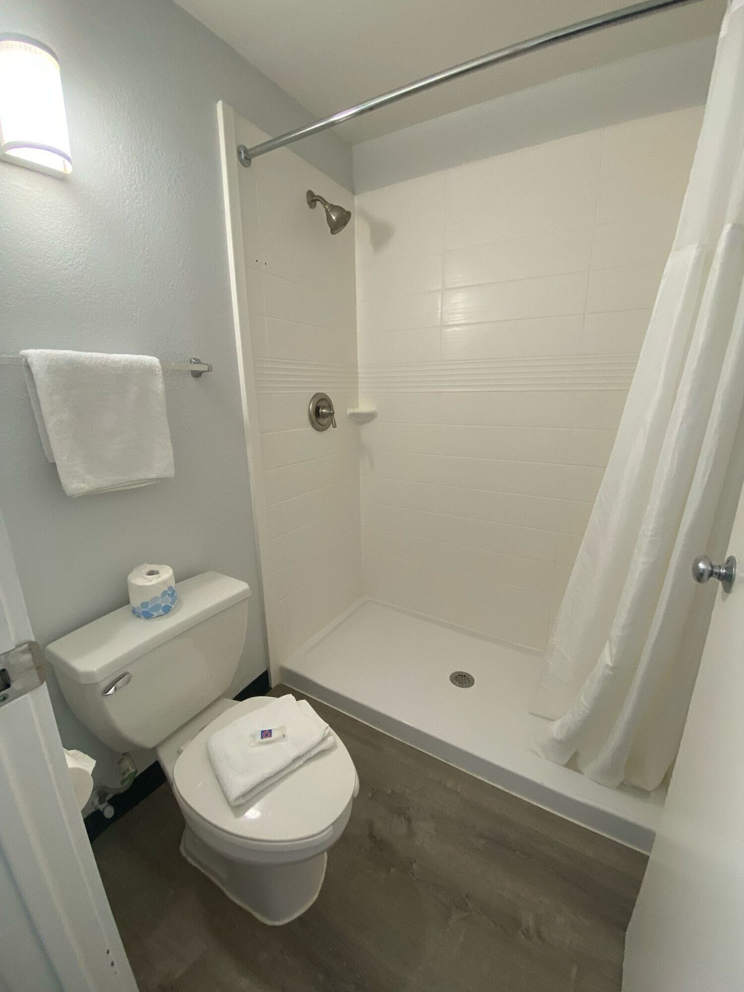 A bathroom with a shower, toilet, and a towel rack.