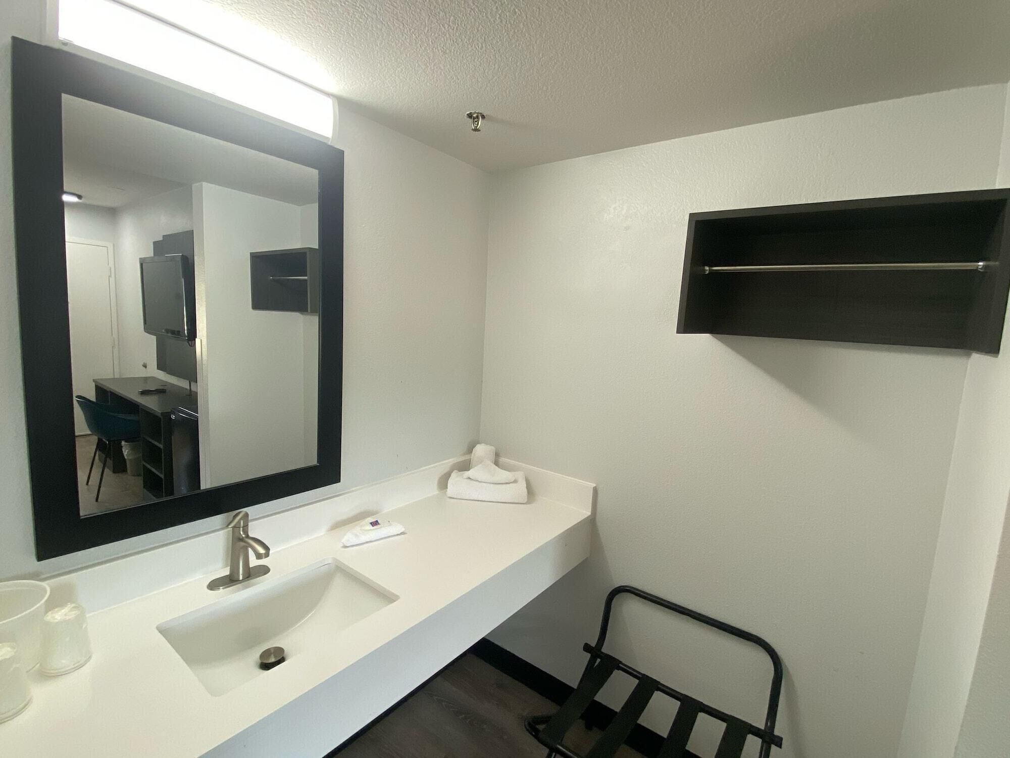 Un baño moderno con un lavabo blanco, un espejo grande y un toallero negro.