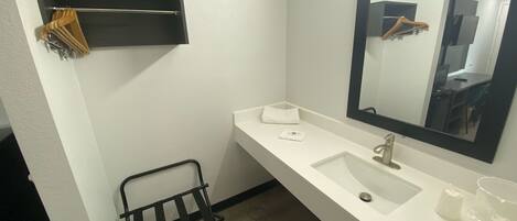 Un baño moderno con un lavamanos blanco, un espejo grande y un perchero para toallas.