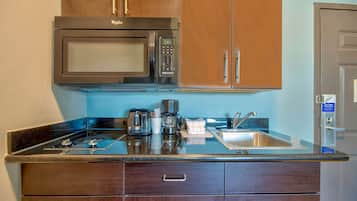A compact kitchen with a built-in microwave, coffee maker, and a stainless steel sink.