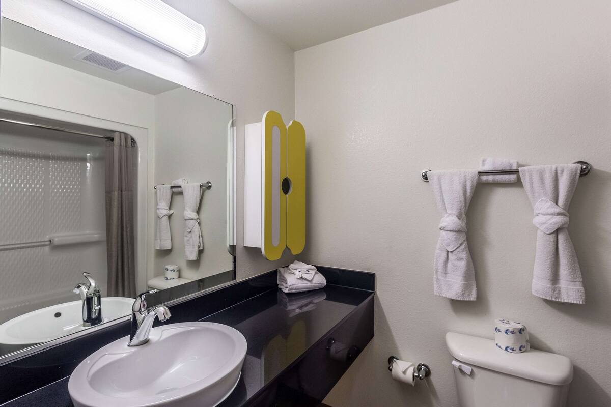 A bathroom with a sink, mirror, towel rack, and toilet.