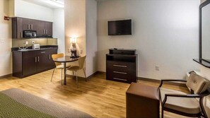 A compact living space with a kitchenette, a dining area, a TV mounted on the wall, and a seating area with a sofa and chairs. - Studio 6 Mcallen, TX (McAllen)