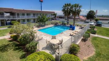 A hotel with a swimming pool, outdoor seating, and a fenced patio area.