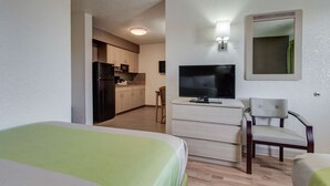 A hotel room with a bed, a TV, a desk, and a chair. There is a kitchenette in the background. - Studio 6 El Paso, TX - East (El Paso)