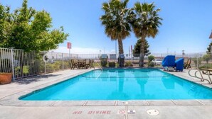 A rectangular swimming pool with a 'NO DIVING' sign, surrounded by a white fence, palm trees, and lounge chairs. - Studio 6 El Paso, TX - East (El Paso)